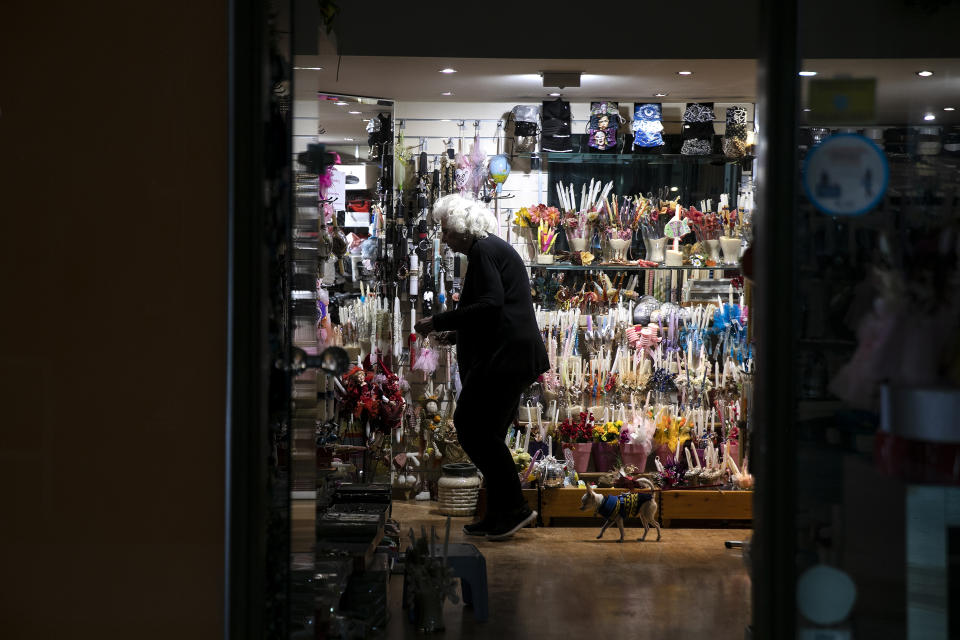 A woman adjusts items inside a shop, at Glyfada suburb west of Athens, Saturday, April 3, 2021. Greece has relaxed some coronavirus restrictions despite surging COVID-19 cases that are straining hospitals to their limits, with retail stores to reopen and people allowed to drive outside their home municipalities for exercise on weekends. AP Photo/Yorgos Karahalis)