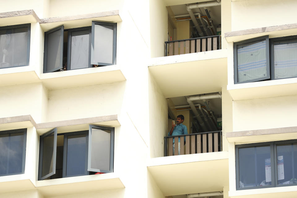 FILE - In this April 10, 2020, file photo, a foreign worker talks on the phone outside his room at the WestLite Toh Guan dormitory after it was declared an isolation area under the Infectious Diseases Act, following a spike in the number of COVID-19 cases in several foreign worker dormitories in Singapore. A second wave of coronavirus infections in tightly packed foreign workers' dormitories has caught Singapore off guard, and exposed the danger of overlooking marginal groups in a health crisis. Infections in Singapore, an affluent Southeast Asian city-state of fewer than 6 million people, have jumped more than a hundredfold in two months — from 226 in mid-March to over 23,000, the most in Asia after China and India.(AP Photo/Yong Teck Lim, File)