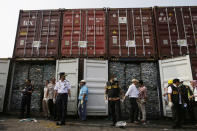 Indonesian customs and police officers stand near containers full of plastic waste at Tanjung Priok Port in Jakarta, Indonesia Wednesday, Sept. 18, 2019. Indonesia is sending hundreds of containers of waste back to Western nations after finding they were contaminated with used plastic and hazardous materials. (AP Photo/Achmad Ibrahim)