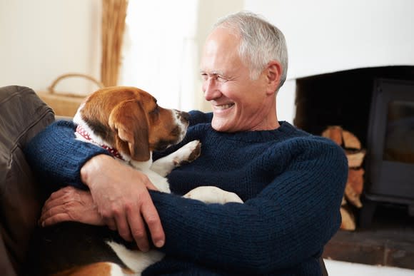 Smiling senior man holding dog.