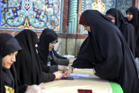 An Iranian woman registers to cast her vote during the parliament elections at a polling station in Tehran, Iran, Friday, Feb. 21, 2020. Iranians began voting for a new parliament Friday, with turnout seen as a key measure of support for Iran's leadership as sanctions weigh on the economy and isolate the country diplomatically. (AP Photo/Ebrahim Noroozi)