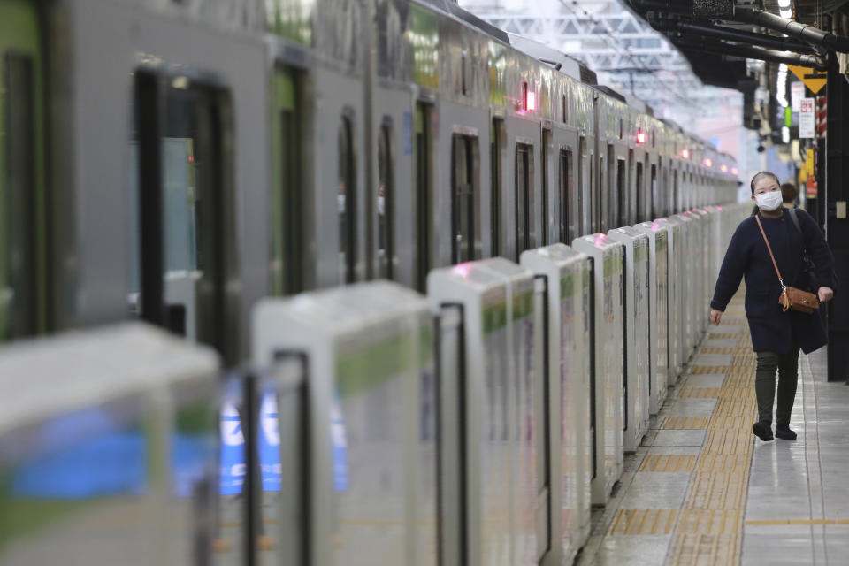 A woman wearing a face mask to protect against the spread of the coronavirus walks along a platform at the train station in Tokyo, Wednesday, Nov. 25, 2020. (AP Photo/Koji Sasahara)