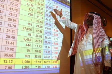 A saudi man inspect a screen showing stock prices at ANB Bank, in Riyadh