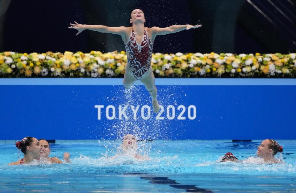 A member of Canada's team is airborne while the other team members are in the water below.