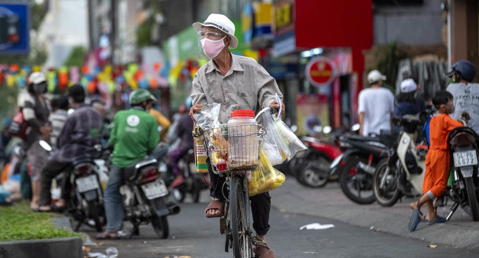 A man rides a bicycle with a mask on during a surge of Covid infections in Vietnam. 