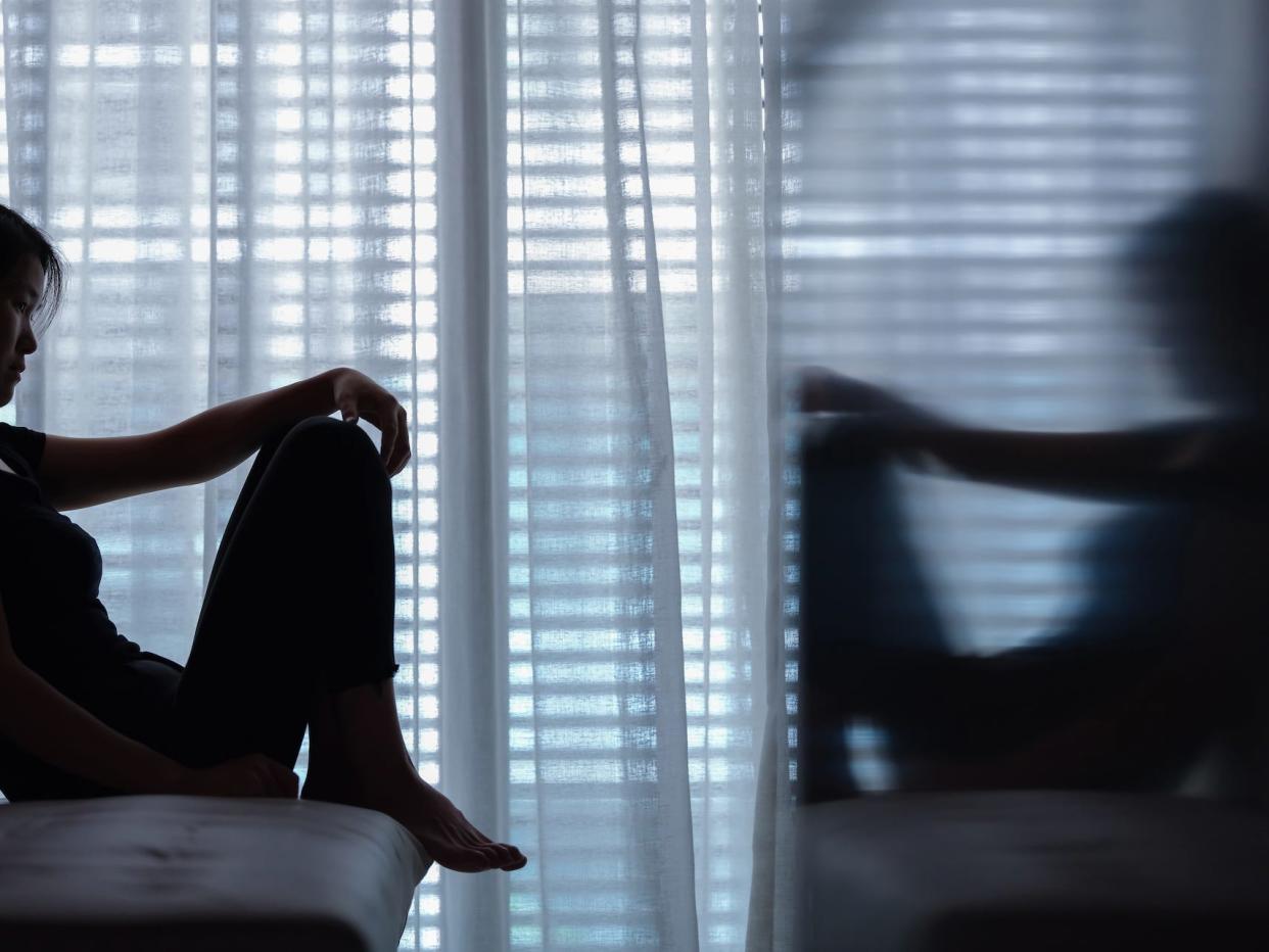 woman sitting on the couch with her reflection facing her