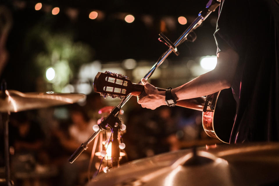 Guitarist performing live on stage at a dimly lit evening venue