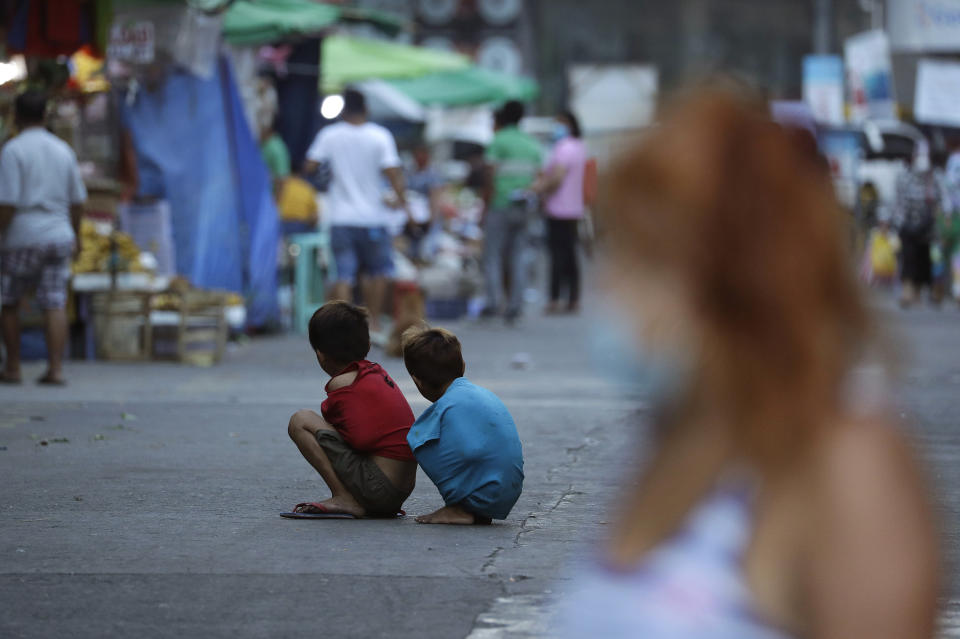 Boys use their shirts to keep warm as they sit in the middle of the street during stricter health protocols at downtown Manila, Philippines on Wednesday, March 24, 2021. The Philippines has reported more than 677,000 confirmed COVID-19 infections, with nearly 13,000 deaths, the highest totals in Southeast Asia after Indonesia. (AP Photo/Aaron Favila)