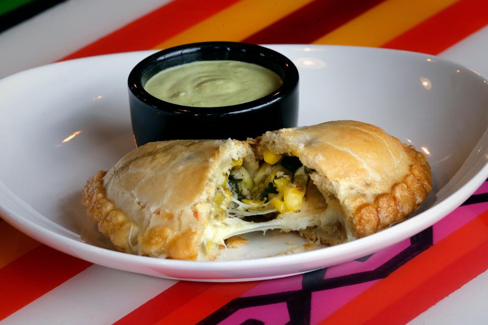 A corn and cheese empanada is served with cilantro sauce at the now-closed Triciclo Peru in Milwaukee. A handful of Milwaukee-area restaurants serve empanadas, which can be stuffed with a variety of fillings.