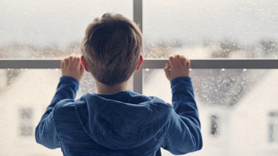 Niño mira por la ventana.