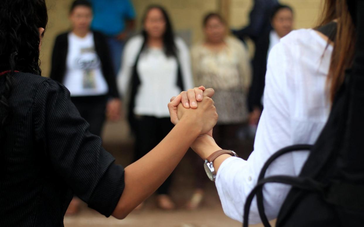 People hold hands while praying for peace in the country outside a vote counting center in Tegucigalpa, Honduras - REUTERS