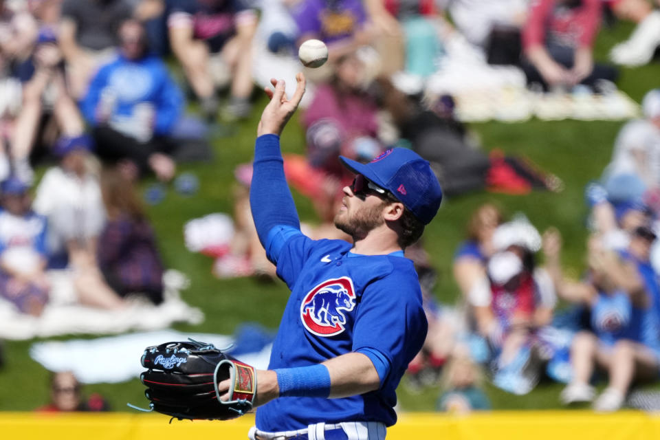 Chicago Cubs left fielder Ian Happ tosses a baseball into the crowd during the third inning of a spring training baseball game against the Texas Rangers Friday, March 24, 2023, in Mesa, Ariz. (AP Photo/Ross D. Franklin)