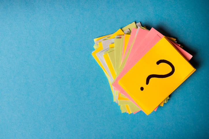 A pile of colorful cards on a blue background, with the topmost card having a question mark drawn on it