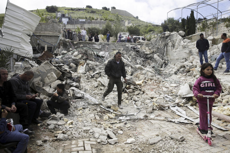 FILE - In this April 17, 2019 file photo, Palestinians watch a family house destroyed by Israeli authorities in east Jerusalem's neighborhood of Silwan. Scores of Palestinian-owned residences in east Jerusalem now face demolition by Israeli authorities after the Supreme Court dismissed residents' appeal on the grounds that the houses were built illegally in a city park. Activists and Palestinian residents of the so-called "Peace Forest" say the case highlights the city's discriminatory housing policies, as construction by a nationalist Jewish organization accelerates in the same park. (AP Photo/Mahmoud Illean, File)