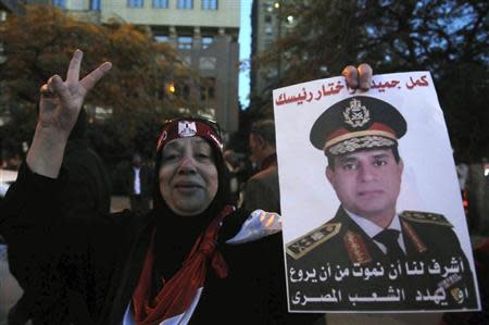 An Egyptian holds an image of Egypt's Army Chief General Abdel Fattah al-Sisi during a protest against what they say is Qatar's backing of ousted Egyptian president Mohamed Mursi's government, outside the Qatari Embassy in Cairo December 6, 2013. REUTERS/Stringer