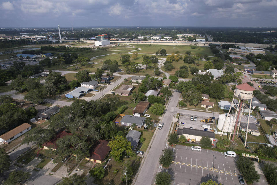 Vacant land that once belonged to the Robert Hungerford Normal and Industrial School is seen past homes in Eatonville, Fla., Thursday, Aug. 24, 2023. Established in 1887, Eatonville was one of the first incorporated self-governing Black municipalities in the U.S. The Hungerford school opened ten years later to educate Black children and became a focal point of community life for generations. A key challenge for present-day residents striving to preserve the town's historical character is the Orange County Public School Board, which owns the 100 acres of property in the middle of town where the school once stood. (AP Photo/Rebecca Blackwell)