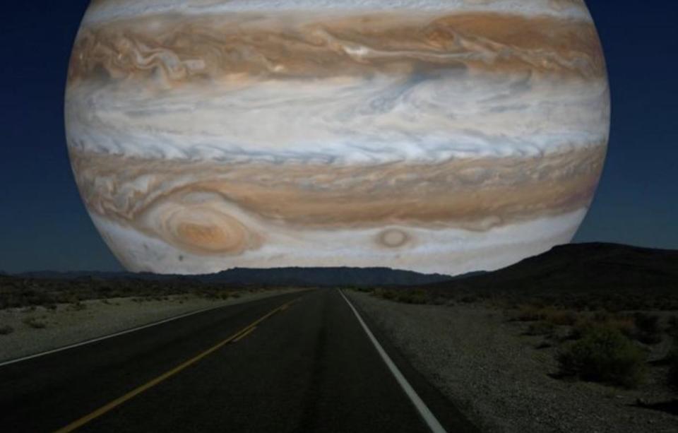 A huge brown and white orb with stripes and swirls on the horizon