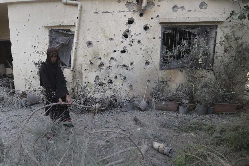 A Lebanese woman removes broken tree branches after her house was hit by Israeli shelling, in Dahaira village, South Lebanon, Monday, Oct. 9, 2023. Israeli troops shot and killed several gunmen who crossed into the country from Lebanon, the Israeli Defense Forces said, without specifying the number of people killed nor their alleged affiliation. (AP Photo/Mohammed Zaatari)