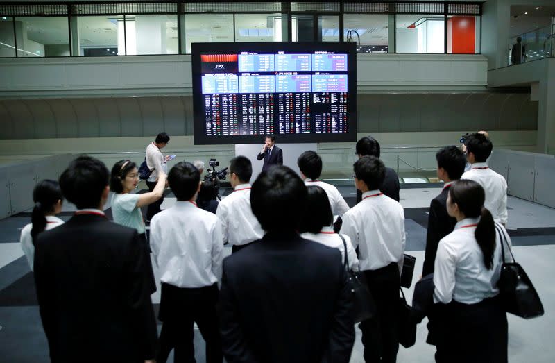 FILE PHOTO: Visitors look at an electronic stock quotation board at the TSE in Tokyo