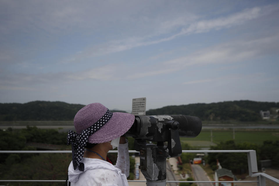 A visitor wearing a face mask uses binoculars to view from the Imjingak Pavilion in Paju, South Korea, Sunday, June 14, 2020. South Korea on Sunday convened an emergency security meeting and urged North Korea to uphold reconciliation agreements, hours after the North threatened to demolish a liaison office and take military action against its rival. (AP Photo/Lee Jin-man)