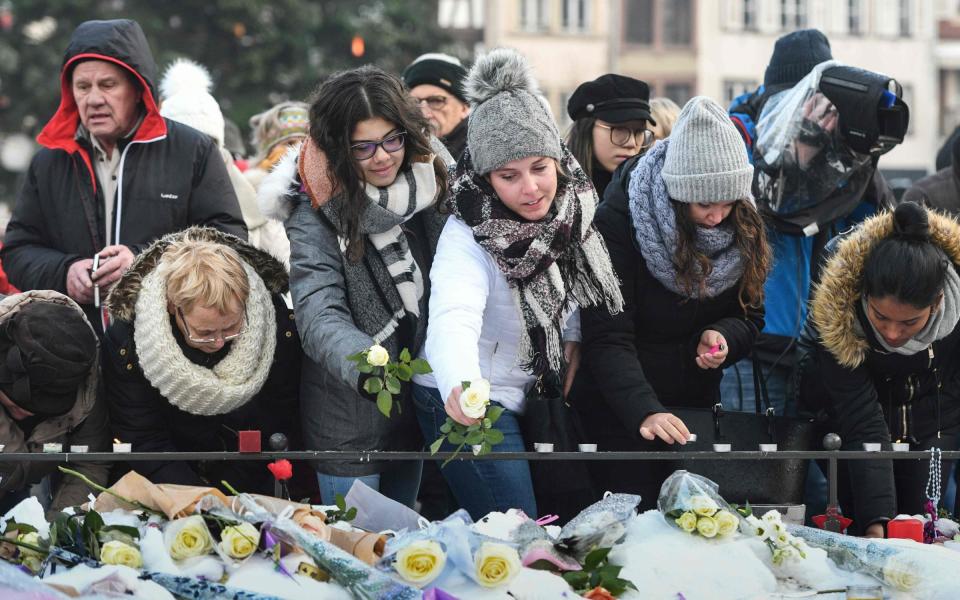 People add flowers to a memorial in Strasbourg - SEBASTIEN BOZON/AFP