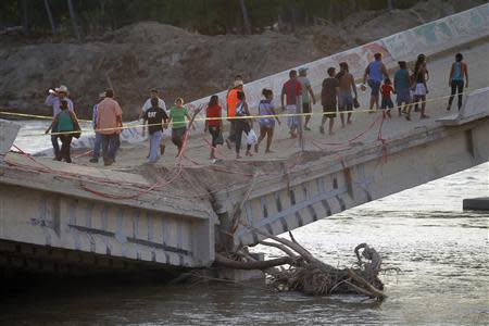 People walk on a collapsed bridge in Coyuca de Benitez on the outskirts of Acapulco, October 2, 2013. REUTERS/Edgard Garrido