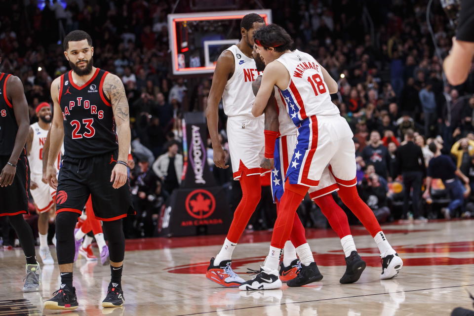 Brooklyn Nets guard Kyrie Irving, center right, is embraced by forwards Yuta Watanabe (18) and Kevin Durant, center left, after hitting the winning basket against the Toronto Raptors during an NBA basketball game in Toronto, Friday, Dec. 16, 2022. (Cole Burston/The Canadian Press via AP)