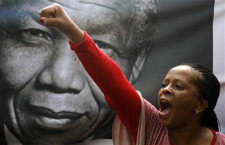 A mourner shouts "Viva Mandela" by a portrait of Nelson Mandela soon after the coffin of former South African President Nelson Mandela travelled through a street in Pretoria, December 11, 2013, on its way to the Union Buildings, where his coffin will lie in state for three days. REUTERS/Yannis Behrakis