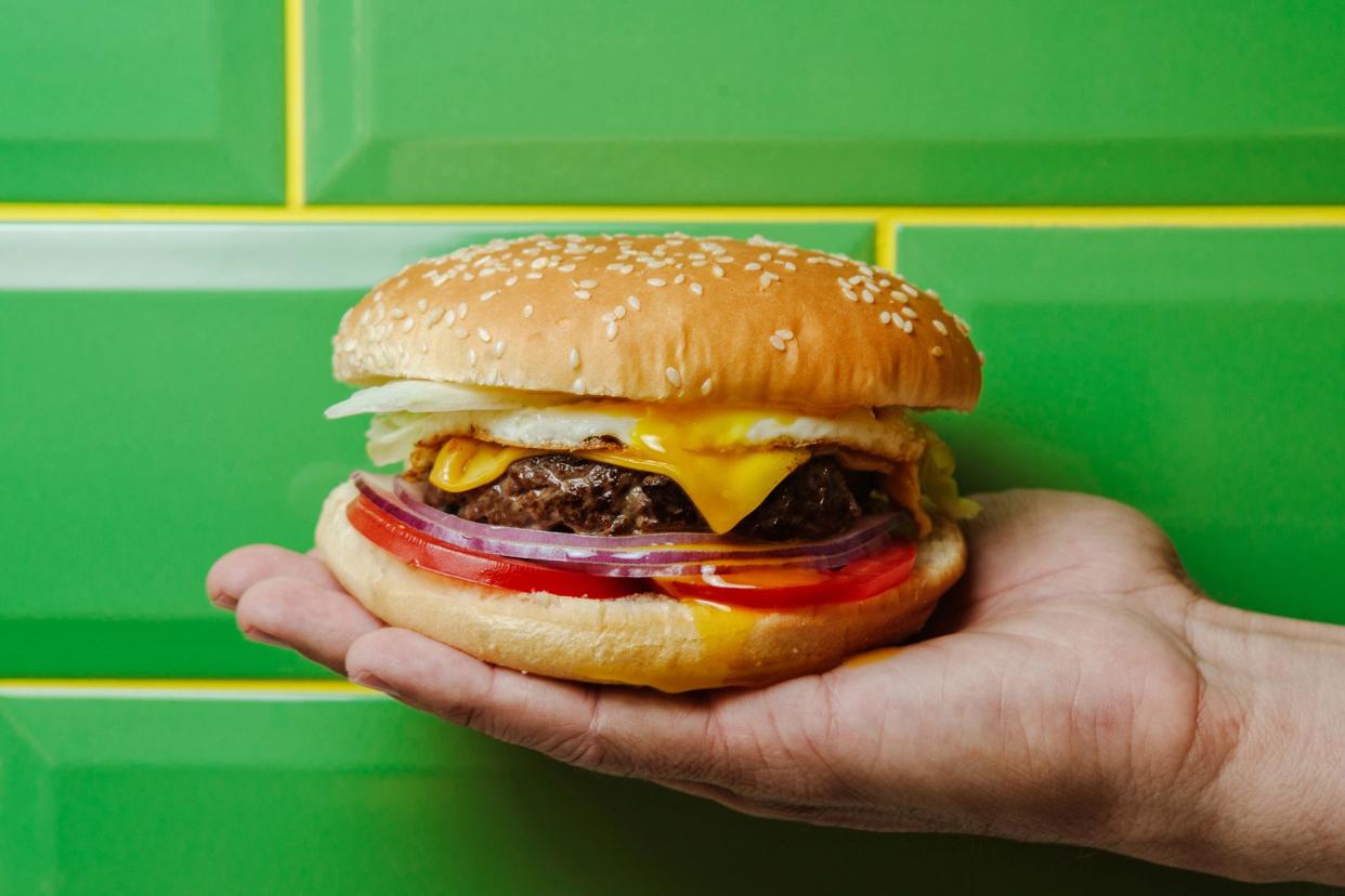 burger in hand, tiled wall in background