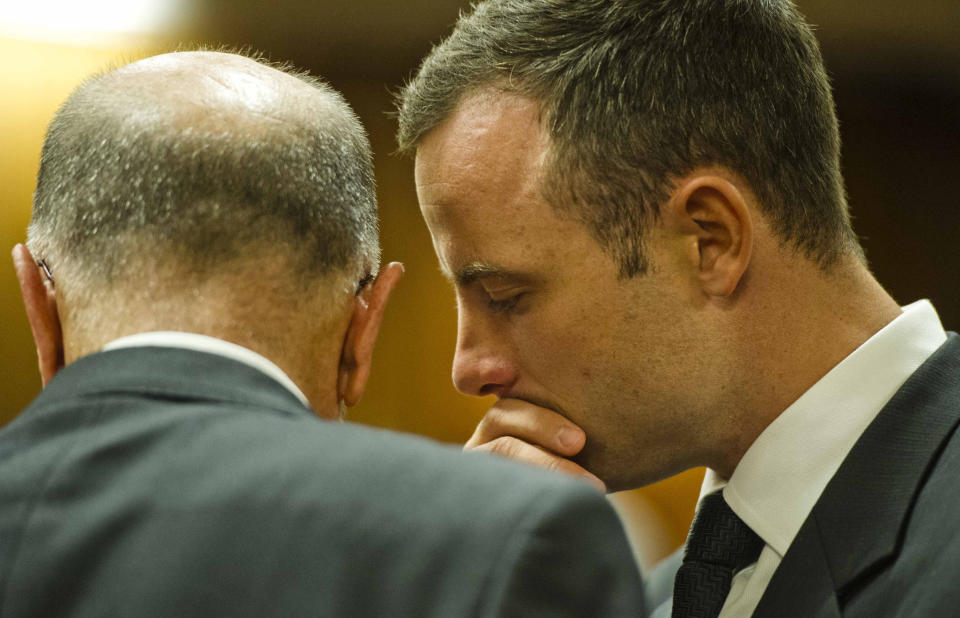 Oscar Pistorius, right, talks with his uncle Arnold Pistorius in court on the fifth day of his trial at the high court in Pretoria, South Africa, Friday, March 7, 2014. Pistorius is charged with murder for the shooting death of his girlfriend, Reeva Steenkamp, on Valentines Day in 2013. (AP Photo/Theana Breugem, Pool)