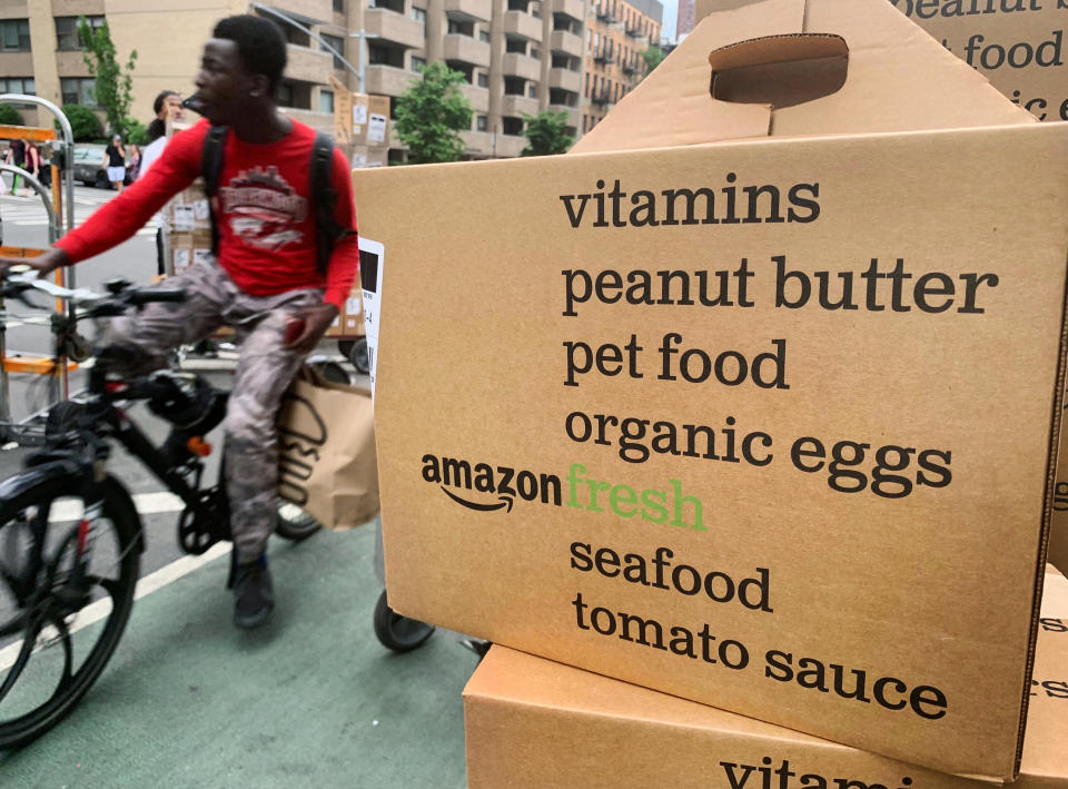 In this Sunday, June 16, 2019, a bike messenger rides past boxes of Amazon Fresh deliveries in New York. With the proliferation of subscription services, mobile payments and other conveniences, it's become easier for consumers to lose track of what they've signed up for and how much it's costing them. (AP Photo/Jenny Kane)