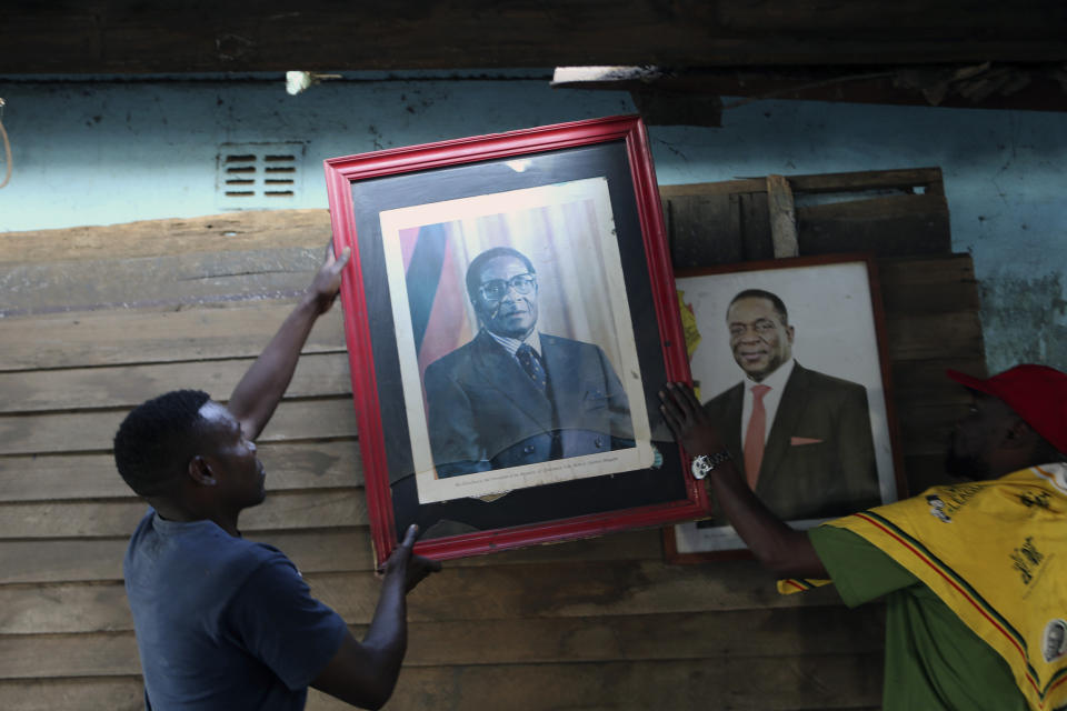 Supporters of former Zimbabwean President Robert Mugabe place his portrait next to that of Zimbabwean President Emmerson Mnangagwa in Harare, Sept, 10, 2019. Mnangagwa declared him a national hero. (AP Photo/Tsvangirayi Mukwazhi, File)