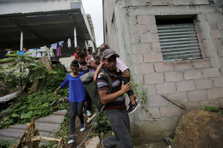 Honduran migrants walk between houses in Agua Caliente hoping to cross into Guatemala and join a caravan trying to reach the U.S, in Honduras October 17, 2018. REUTERS/Jorge Cabrera
