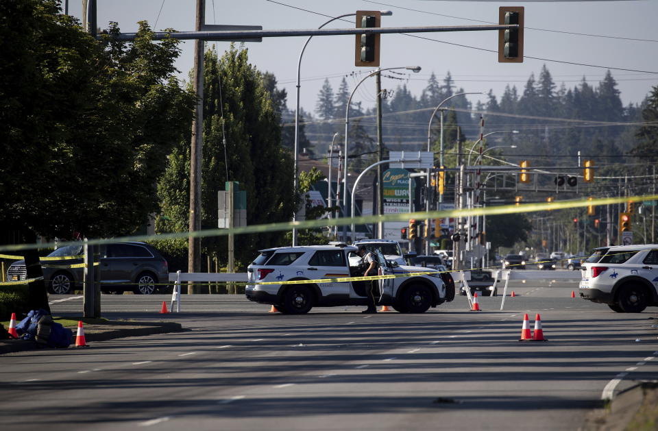 An RCMP officer stands outside a vehicle at a roadblock at the scene of a shooting in Langley, British Columbia, Monday, July 25, 2022. Canadian police reported multiple shootings of homeless people Monday in a Vancouver suburb and said a suspect was in custody. (Darryl Dyck/The Canadian Press via AP)