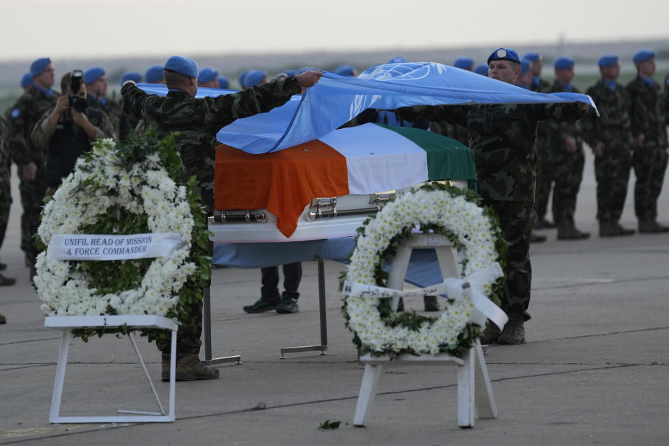 Irish U.N peacekeepers take off the United Nations flag from over the coffin of their comrade Pvt. Seán Rooney who was killed during a confrontation with residents near the southern town of Al-Aqbiya on Wednesday night, during his memorial procession at the Lebanese army airbase, at Beirut airport, Sunday, Dec. 18, 2022. (AP Photo/Hussein Malla)