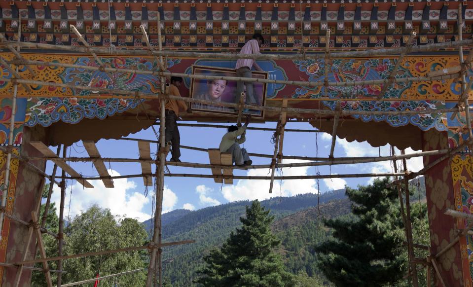 Men hang a portrait of Bhutan's king and fiancee on an archway in Bhutan's capital Thimphu