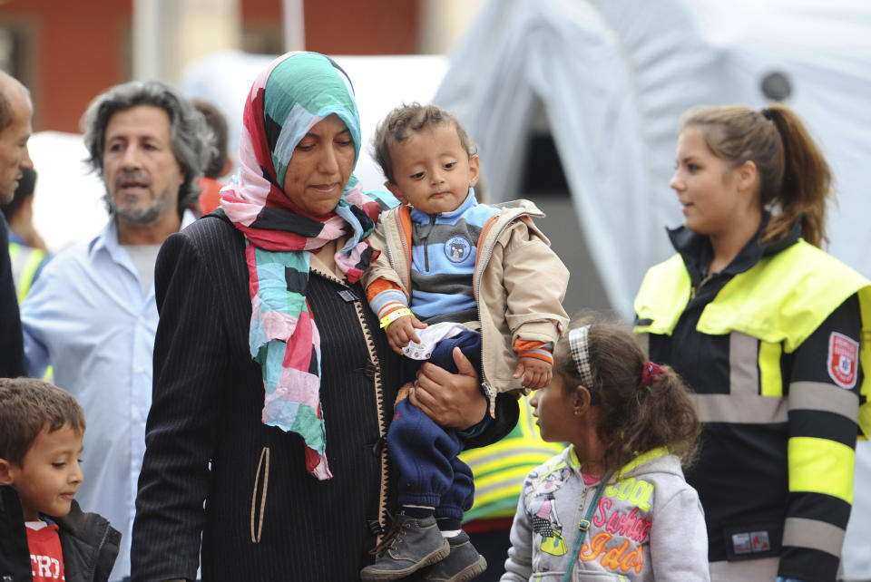 FILE- In this Sept. 8, 2015 file photo a woman and a child, along with other migrants and refugees, are transferred to a train bound for another German city, shortly after their arrival in Munich. Germany says that for the first time it has transferred more asylum seekers to other European Union countries than it took in from other EU countries. (Andreas Gebert/dpa via AP)