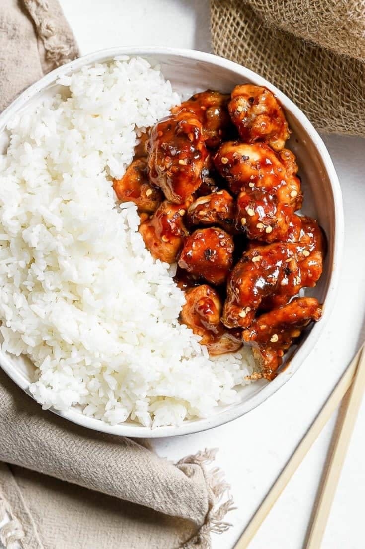 A bowl of white rice with crispy General Tso's chicken