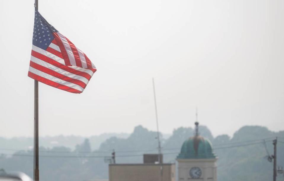 A flag waves outside of the sheriff’s office but smoke and haze distorts the view of the courthouse clock tower and beyond on Thursday, June 29, 2023.