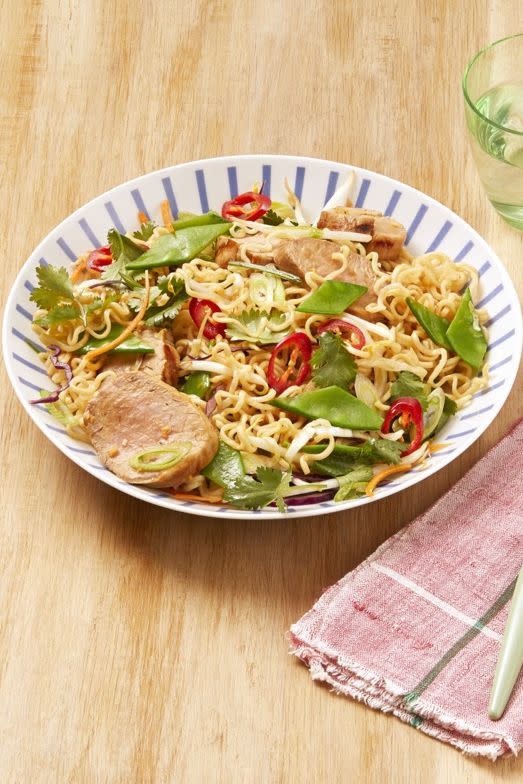 sesame pork noodle salad in bowl on wood surface