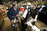 In this March 24, 2020, photo David Leeson, of Winterset, Iowa, pays for his groceries at the Gateway Market in Des Moines, Iowa. While most governors have imposed stay-at-home orders to slow the spread of the coronavirus, leaders of a handful of states have rejected such action. (AP Photo/Charlie Neibergall)