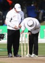 Umpire Aleem Dar (right) fits heavier bails on top of the stumps with reserve umpire Gav Baxter after the wind blew them off during Day 4 of the first Test match between New Zealand and South Africa at the University Oval in Dunedin on March 10, 2012.