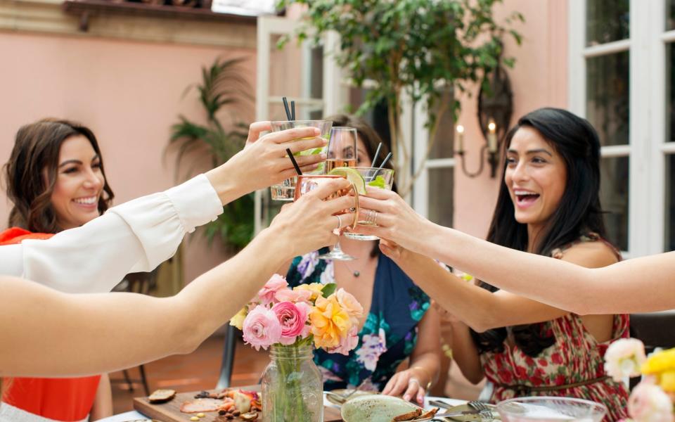 Happy female friends toasting drinks at outdoor restaurant - Getty Images/Cavan Images