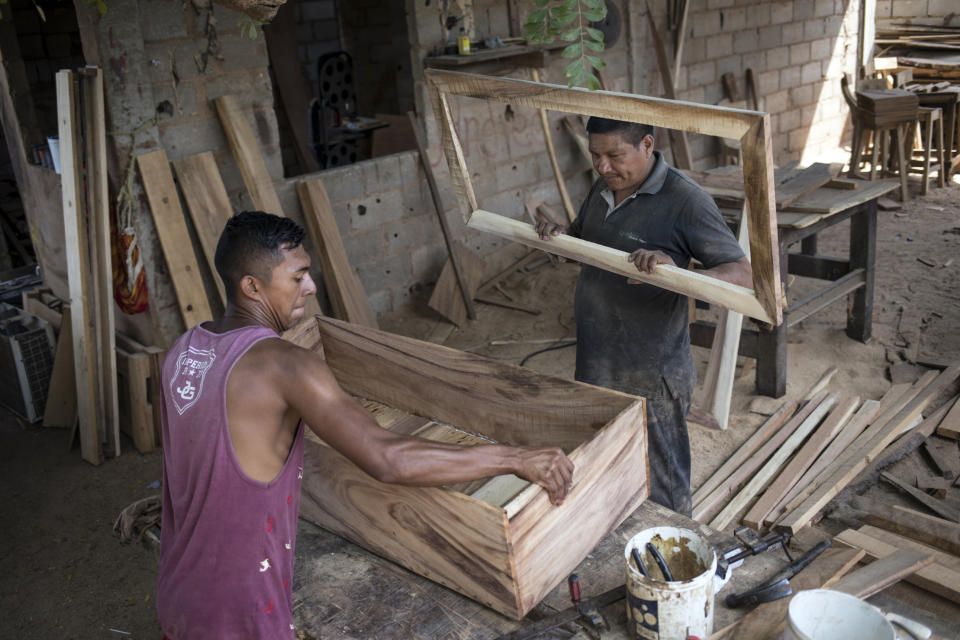 Sergio Morales, right, and Joelvis Cantillo, build a simple coffin at their furniture workshop in Maracaibo, Venezuela, Nov. 20, 2019. Two years ago the carpenters started building coffins for less than $100 instead of furniture due to the high demand for cheaper coffins. (AP Photo/Rodrigo Abd)