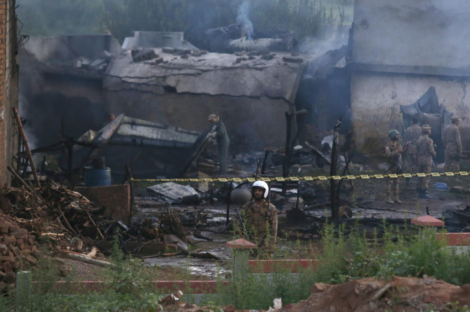 Pakistan army officials examine the site of a plane crash in Rawalpindi, Pakistan, Tuesday, July 30, 2019. A small Pakistani military plane crashed into a residential area near the garrison city of Rawalpindi before dawn, killing some people, officials said. (AP Photo/Anjum Naveed)