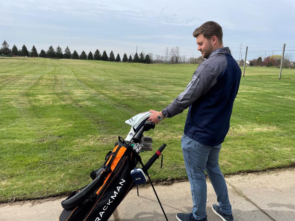 Tap-In's co-founder Cade Martin grabs a club out of his golf bag near a stretch of green where a new driving range will go, shown Thursday, May 5, 2022.
