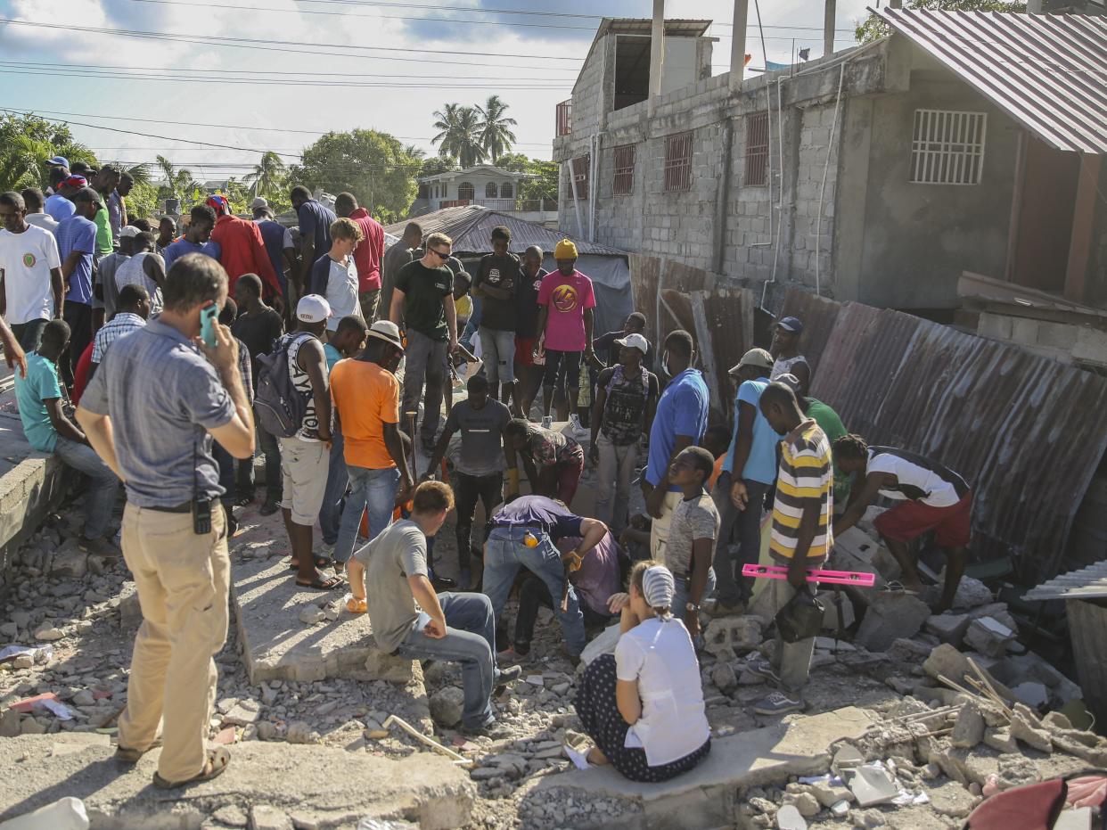 People search for survivors in the debris of a home destroyed by the earthquake in Les Cayes, Haiti, Saturday, Aug. 14, 2021.