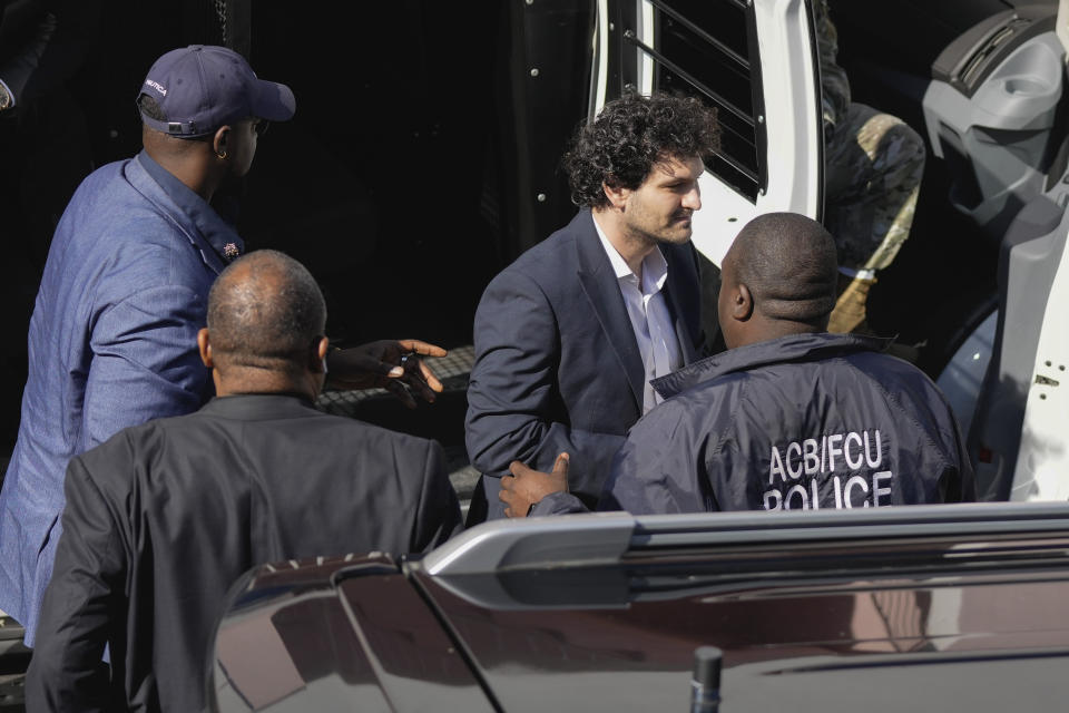 FTX founder Sam Bankman-Fried, center, is escorted from a Corrections Department van as he arrives at the Magistrate Court building for a hearing, in Nassau, Bahamas, Wednesday, Dec. 21, 2022.(AP Photo/Rebecca Blackwell)