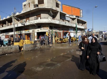 People walk past the site of a blast in Baghdad's Bab Sharji district, March 29, 2016. REUTERS/Khalid al Mousily