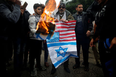 Palestinians burn signs depicting an Israeli flag and a U.S. flag during a protest against the U.S. intention to move its embassy to Jerusalem and to recognize the city of Jerusalem as the capital of Israel, in Gaza City December 6, 2017. REUTERS/Mohammed Salem